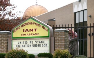 A Muslim woman peers out as protests take place outside a mosque in Richardson, Texas, Dec. 12, 2015. (AP Photo/LM Otero)